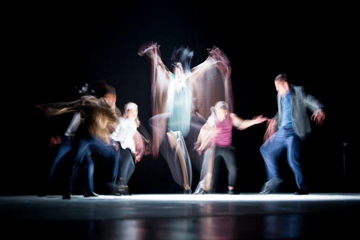 A long exposure image of performers dancing under a spotlight.